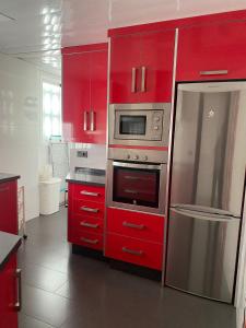 een keuken met rode kasten en een roestvrijstalen koelkast bij Alojamiento Carioca in Almodóvar del Río