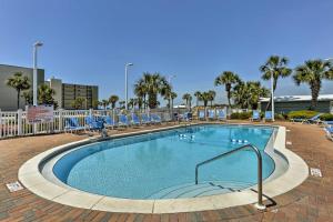 a large swimming pool with blue chairs and trees at Beachfront Panama City Condo with Balcony and Views! in Panama City
