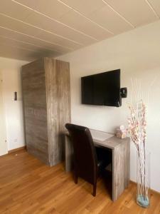 a desk with a chair and a television on a wall at Apartment mit Rheinblick Koblenz in Koblenz