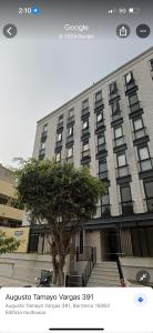Friendly Apartment Tamayo في ليما: مبنى كبير امامه شجرة