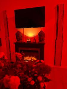 una sala de estar de color rojo con chimenea y TV encima. en Wellness Suite mit Whirlpool und Sauna, en Ahlen