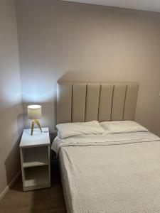 a bedroom with a bed and a lamp on a night stand at Friendly Apartment Tamayo in Lima