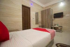 a hotel room with a bed and a television at Capital O Hotel Priyanshu in Siliguri