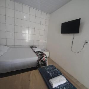 a small room with a bed and a flat screen tv at Pousada Estelita in Itaparica Town