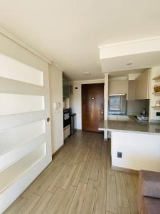 a large kitchen with a wooden floor and a door at Hermosos Dptos cercanos a metro y centros comerciales in Santiago