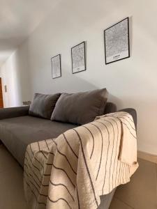 eine Couch in einem Wohnzimmer mit drei Bildern an der Wand in der Unterkunft BHIaparts-Roca con COCHERA in Bahía Blanca