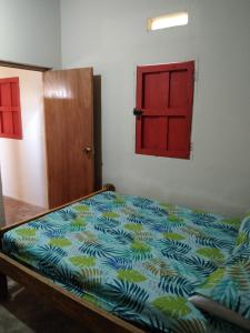 Cama en habitación con puerta roja en Finca hostal La Alicia 1950, en Santa Marta