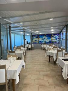 a restaurant with white tables and chairs and a mural at Hotel Villa Maria in Revilla de Camargo