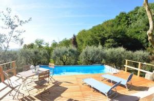 una terraza de madera con sillas y una piscina en Ferienhaus mit Privatpool für 4 Personen ca 50 qm in Loppeglia, Toskana Provinz Lucca, en Loppeglia