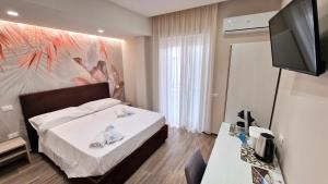 a hotel room with a bed and a flat screen tv at ARIA DI MARE LUXURY B&B in Schiavonea