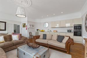 a living room with two couches and a kitchen at Laston Garden Apartment - Sea Views Large Terrace in Tenby