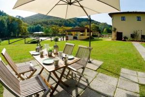 Monsagrati的住宿－Ferienwohnung für 4 Personen ca 50 qm in Monsagrati, Toskana Provinz Lucca，院子里的桌椅和雨伞