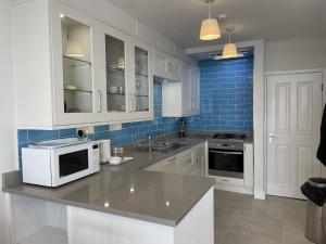 a kitchen with white appliances and blue tiles at Lovely seafront 2 bedroom Apartment 4 in Aberdyfi