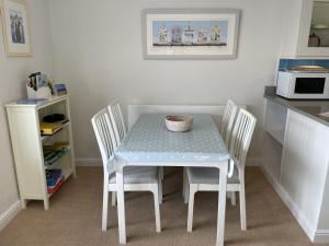 mesa de cocina con sillas, mesa y microondas en Lovely seafront 2 bedroom Apartment 4, en Aberdyfi