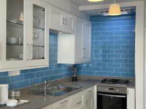 a kitchen with a sink and blue tiles on the wall at Lovely seafront 2 bedroom Apartment 4 in Aberdyfi