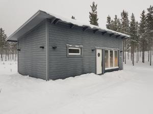 un petit bâtiment dans la neige dans les bois dans l'établissement Gäststuga, nära Piteå havsbad., à Piteå
