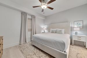 une chambre blanche avec un lit et un ventilateur de plafond dans l'établissement Sea Glass 213, à Gulf Shores