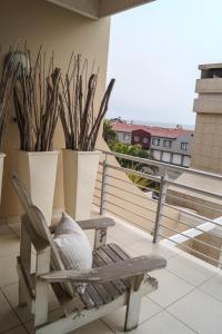 a wooden chair sitting on a balcony with plants at Logis König in Swakopmund