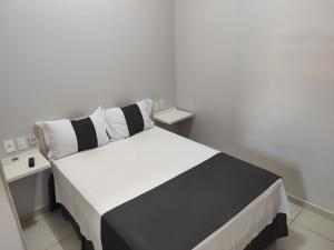 a black and white bed in a white room at Hotel American in Ariquemes
