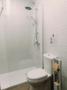 a white bathroom with a toilet and a shower at Apartamento Praia da Gale in Albufeira