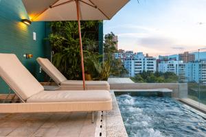 uma varanda com uma banheira de hidromassagem, cadeiras e um guarda-sol em Celestino Boutique Hotel em Medellín