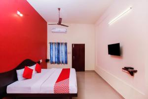 a room with a bed with a red wall at Hotel Aljemin in Kanyakumari