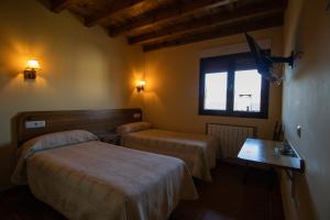 a hotel room with two beds and a window at La Guarida de la Lleira in Ferreras de Arriba
