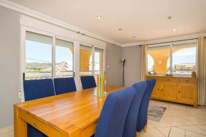 uma sala de jantar com uma mesa de madeira e cadeiras azuis em Felderhof Villa 4 bed Private Pool em Busot