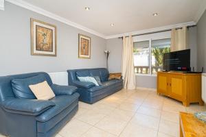 uma sala de estar com dois sofás azuis e uma televisão em Felderhof Villa 4 bed Private Pool em Busot