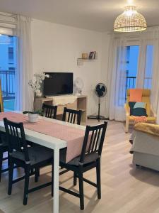 a living room with a table and chairs and a television at Appart Charme Contemporain et Balcon Verdoyant à Bois-Colombes in Bois-Colombes