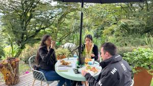 a group of people sitting at a table under an umbrella at Casa Quincha Glamping in San Francisco