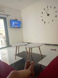 a person with their feet on two tables in a room with a clock at Villa Vielet Lalovina in Mahajanga