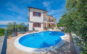 une villa avec une piscine en face d'une maison dans l'établissement Ferienwohnung für 3 Personen ca 35 qm in Drenje, Istrien Bucht von Raša, à Labin