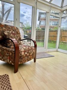 a chair sitting in a room with windows at StayViva - Spacoius 3 BR House - Garden, Games Room, Parking near Town Centre and Train station in Bracknell