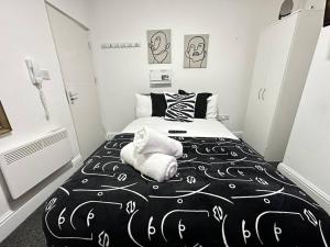 a bedroom with a black and white bed with towels on it at Cosy Chic Flat in the Heart of Kidderminster in Kidderminster