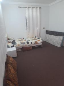 1 dormitorio con 1 cama y una ventana con cortinas en شقة في جعلان ( بيت عربي) اجار يومي واسبوعي en Şūr Maşīrah