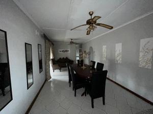 uma sala de jantar com uma mesa e cadeiras e uma ventoinha de tecto em Zinoma guest house em Empangeni
