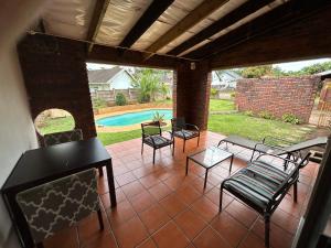 um pátio com cadeiras, uma mesa e uma piscina em Zinoma guest house em Empangeni