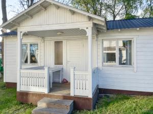 a small white house with a porch and a deck at Strandbergs Stugor in Mariehamn