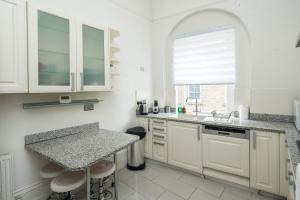 a kitchen with white cabinets and a sink and a window at Four Beds by the Station in London