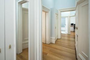 a hallway with white walls and wooden floors and doors at Four Beds by the Station in London