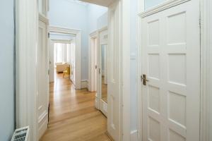 a hallway with white doors and wood floors at Four Beds by the Station in London