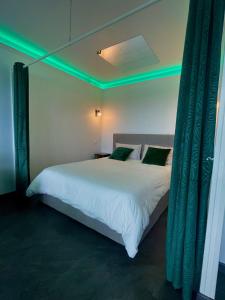 - une chambre avec un grand lit blanc et des lumières vertes dans l'établissement L’Escapade SPA Sauna + Jacuzzi, à Saint-Brieuc
