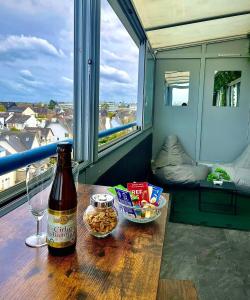 Una botella de cerveza sentada en una mesa en un balcón en L’Escapade SPA Sauna + Jacuzzi en Saint-Brieuc