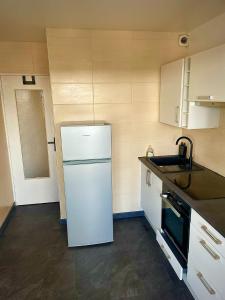 La cuisine est équipée d'un réfrigérateur blanc et d'un évier. dans l'établissement L’Escapade SPA Sauna + Jacuzzi, à Saint-Brieuc