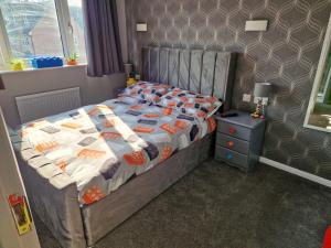 a bedroom with a bed and a nightstand next to a window at The Lego themed house in Windsor