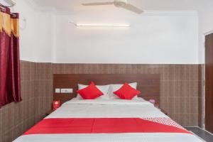 a bedroom with a large bed with red pillows at Capital O Hotel Srinivasa Residency in Tirupati