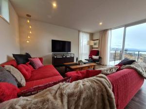 salon z czerwoną kanapą i telewizorem w obiekcie Stunning Views, 2 Bedroom 2 minutes to town centre w mieście Queenstown