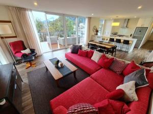 salon z czerwoną kanapą i kuchnią w obiekcie Stunning Views, 2 Bedroom 2 minutes to town centre w mieście Queenstown