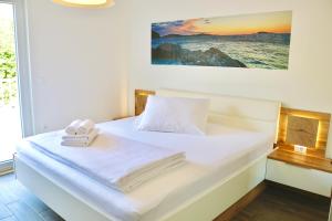 ein Schlafzimmer mit einem weißen Bett und Handtüchern darauf in der Unterkunft Marojica Apartments 2 in Cavtat
